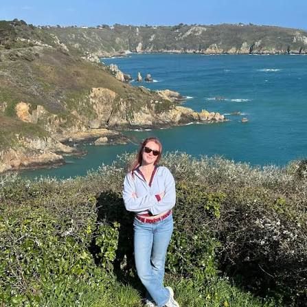 Rosalie standing on the cliffs above a turquoise bay on the Guernsey coast